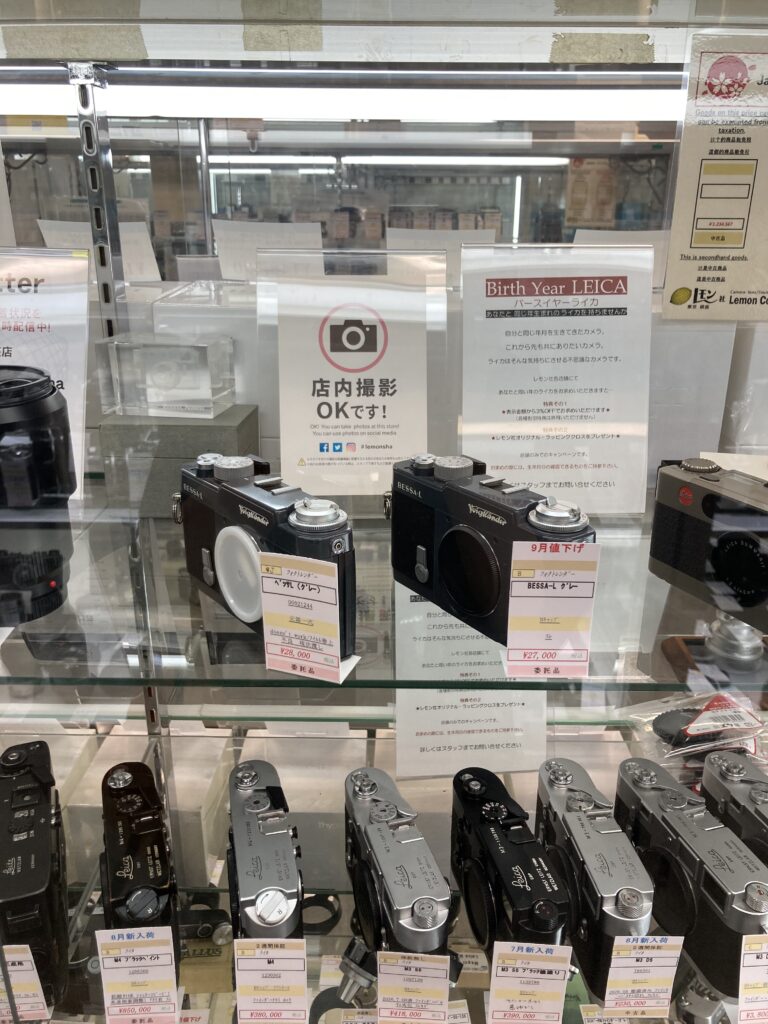 A sign welcoming photography inside the shop, next to a shelf of Leica M bodies
