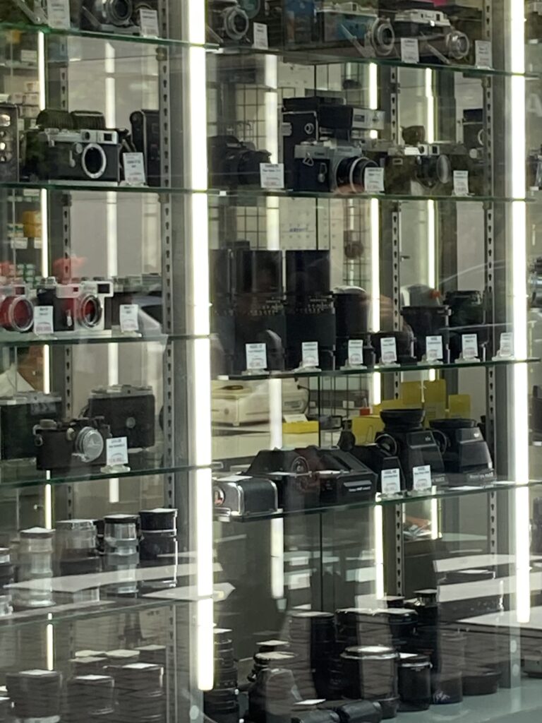 Classic cameras on the shelves inside the show window, visible from the pavement