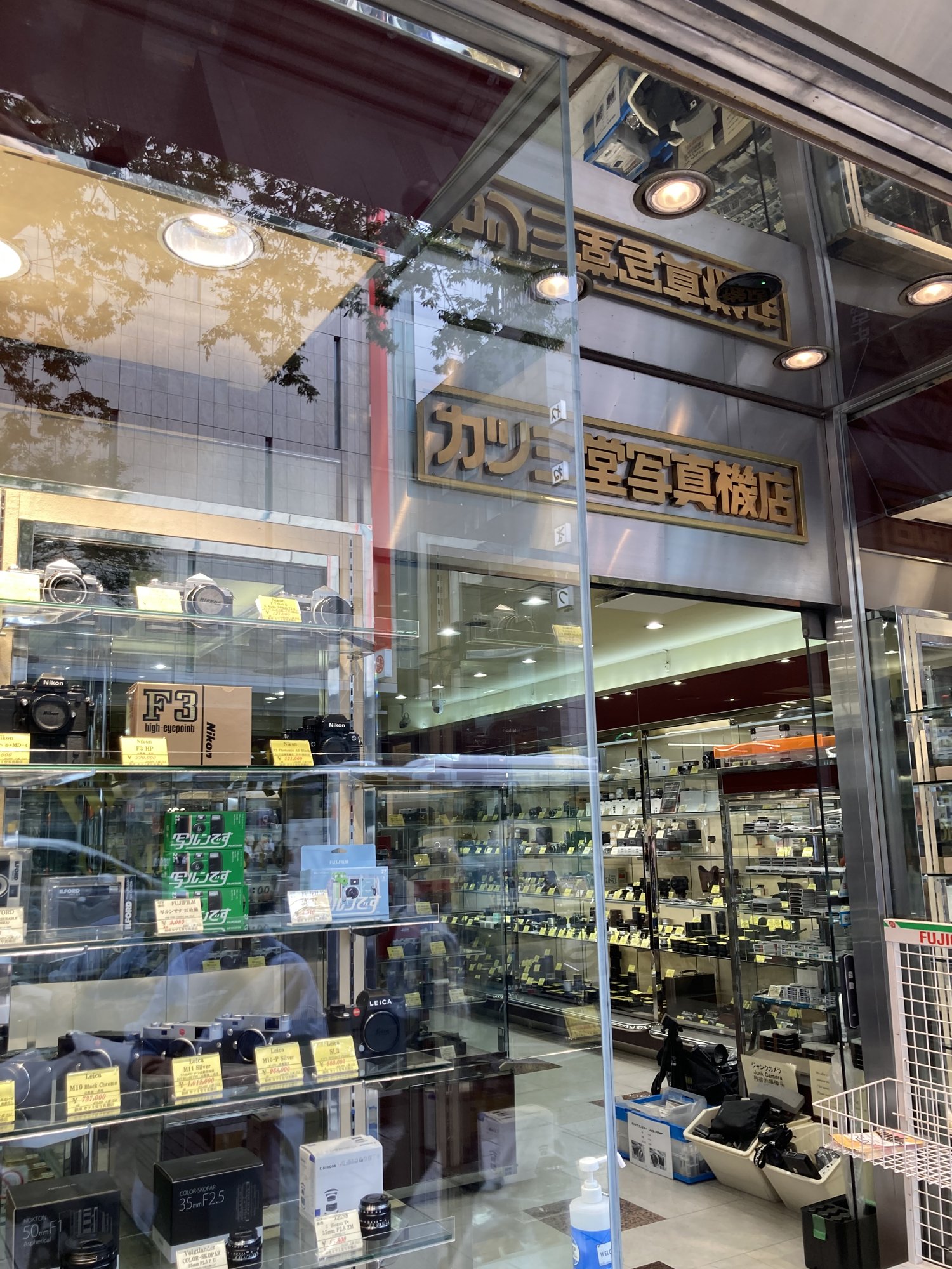 Boxed Nikon F3 High-Eyepoint priced at 220,000 yen in the Katsumido Camera window, below the gold shop sign