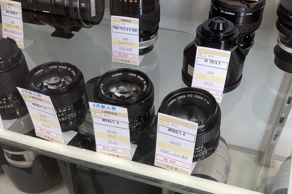 Three Canon New FD 50mm f/1.4 lenses with price tags of 10,000, 10,000 and 9,000 yen in a showcase at Lemon Camera Ginza